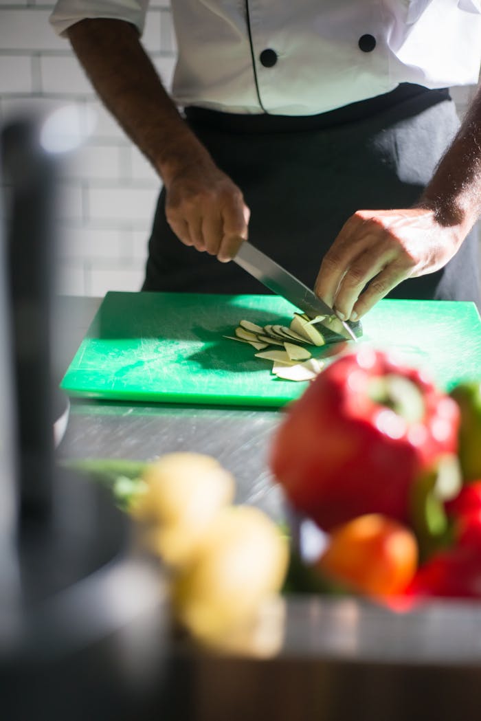why-choose-us A chef expertly slices vegetables on a cutting board in a well-lit kitchen setting.