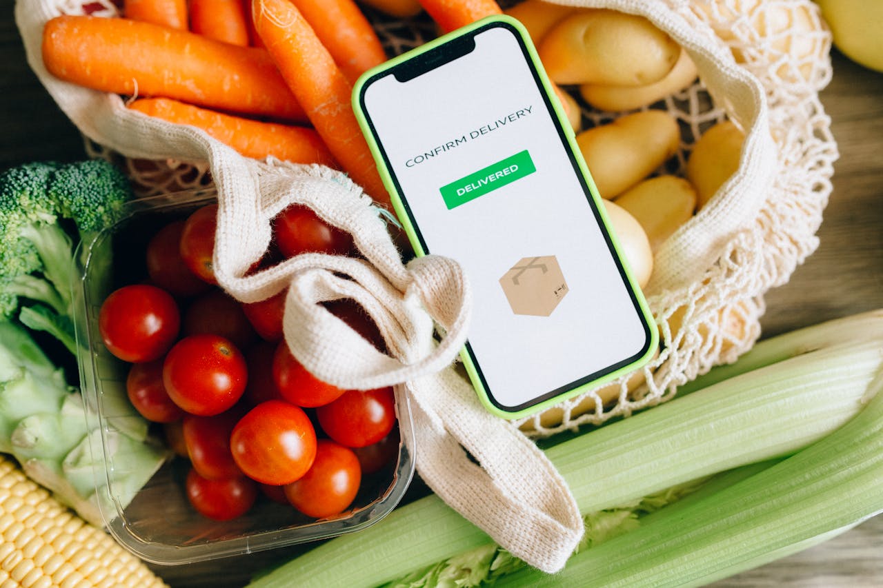 our-services-3 A smartphone displays delivery confirmation amidst fresh vegetables, signifying convenience and freshness.